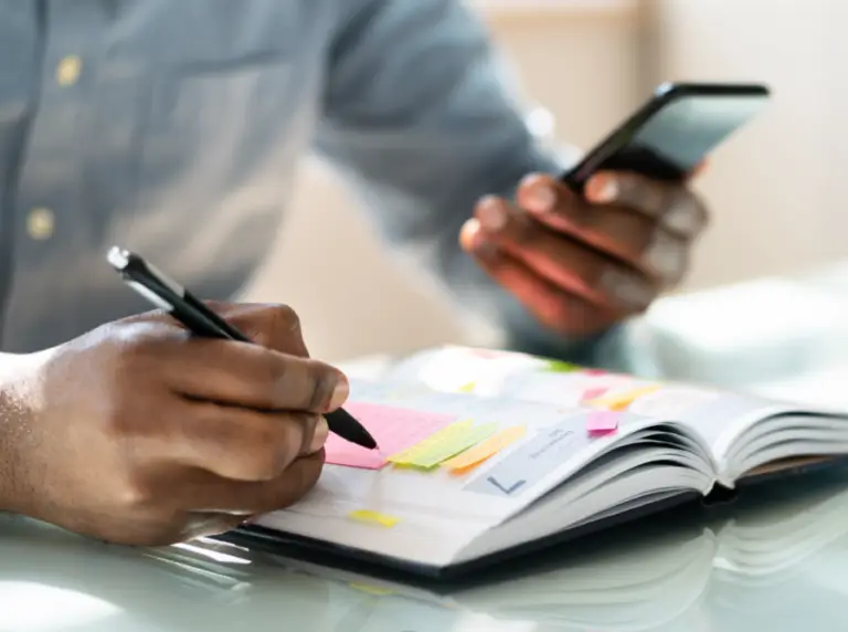 Person managing a work schedule with a diary, highlighting scheduling automation for trade businesses.