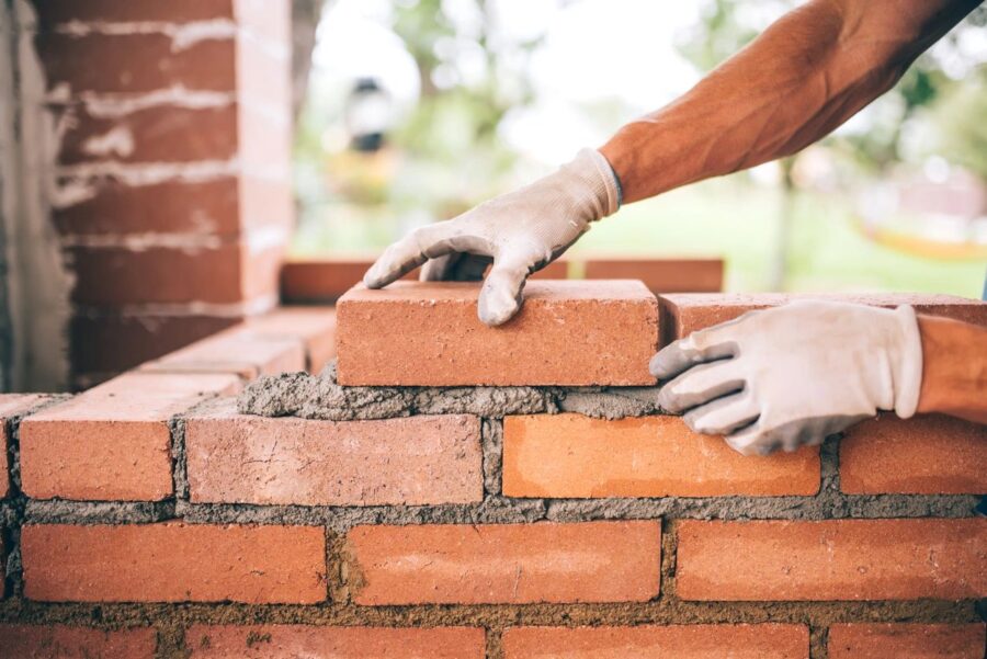 Picture of hand laying bricks with white gloves