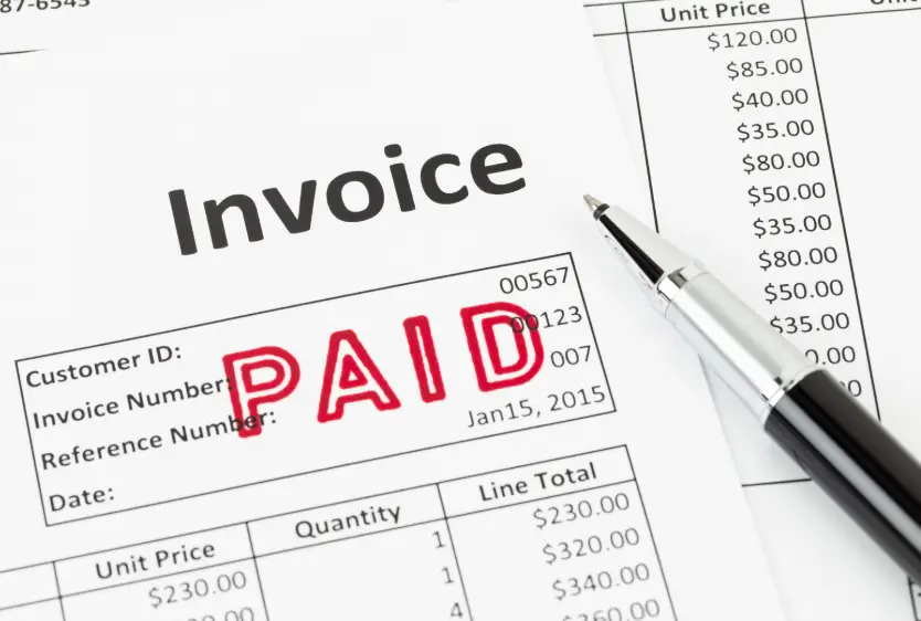 A paper invoice with a red "Paid" stamp, symbolising successful invoicing automation.