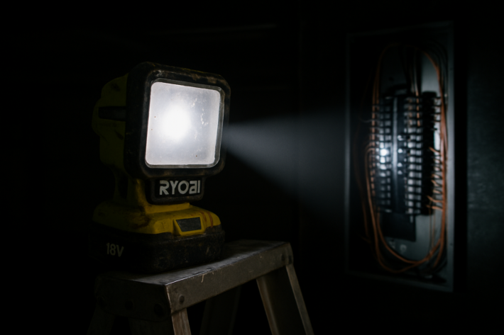 Ryobi LED work light illuminating electrical panel in dark garage for Google Ads electricians guide